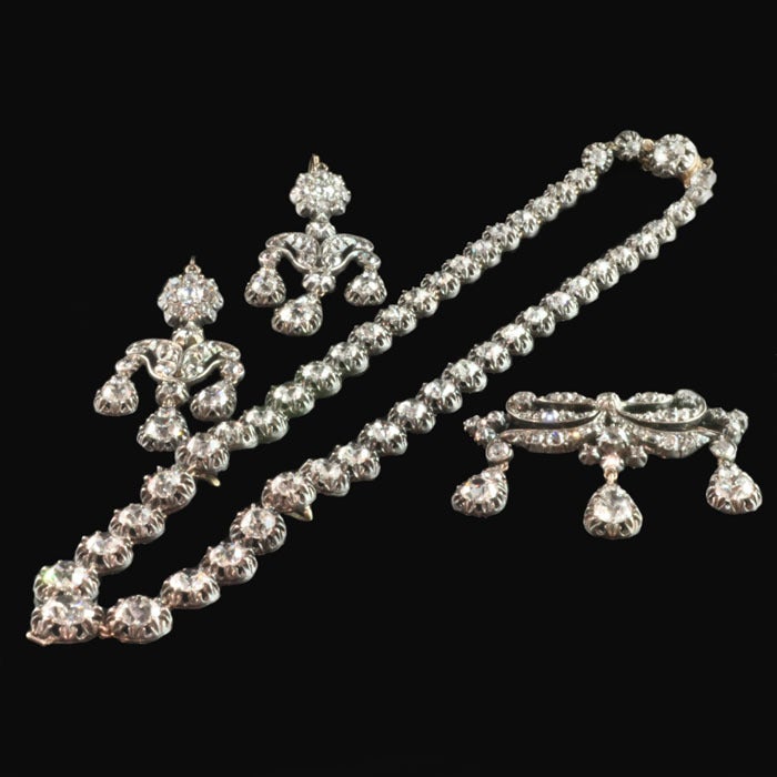 Beautiful suite of diamond jewellery set 'en girandole' and comprising agraduated diamond riviere necklace with detachable brooch-pendant of foliate scroll design and a pair of earrings ensuite English circa 1830