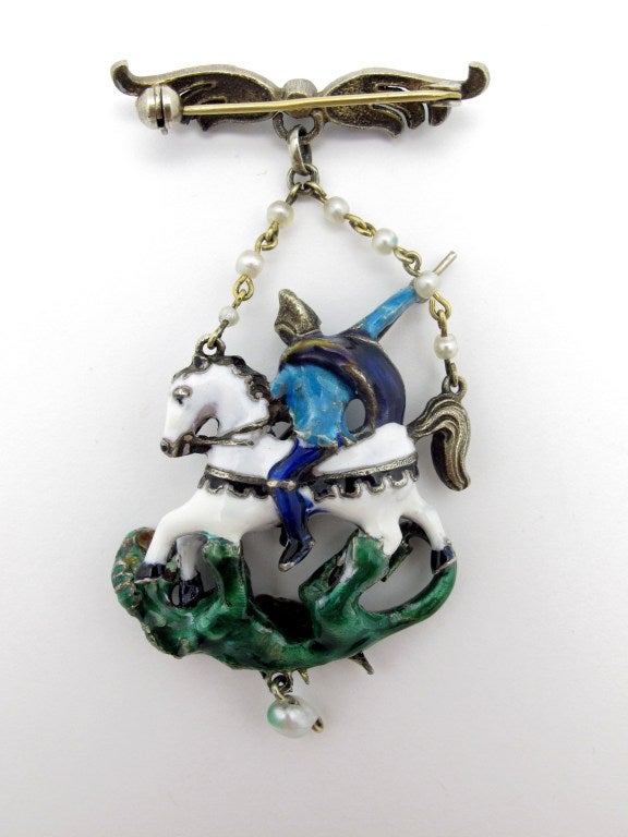 A beautiful 19th century Austro-Hungarian brooch depicting Saint George slaying the dragon. The piece consists of polychrome enamel over silver with a pearl chain and pearl drop. The pearls have not been tested to be natural or cultured.