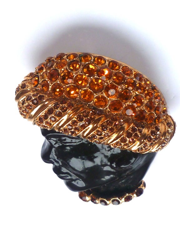 Large and impressive Christian Dior Haute Couture pendant brooch of black resin as a face in profile set on a gilt metal base, with numerous honey and brown colored Swarovsky crystals making a sumptuous turban and a collar. Circa 1980.
Can be worn