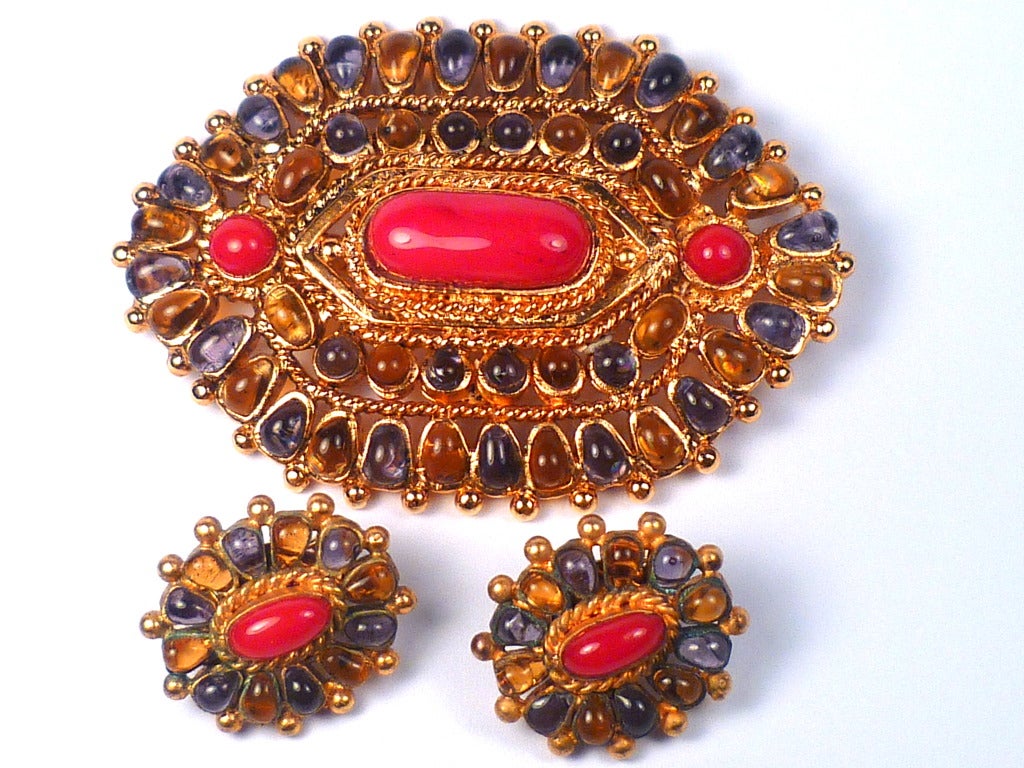 A beautiful and large Byzantine style Chanel brooch for Haute Couture Autumn 1993. Sophisticated gilt metal setting with amber and amethyst colored poured glass jewels surrounding three opaque red poured glass center jewels. All made by Gripoix