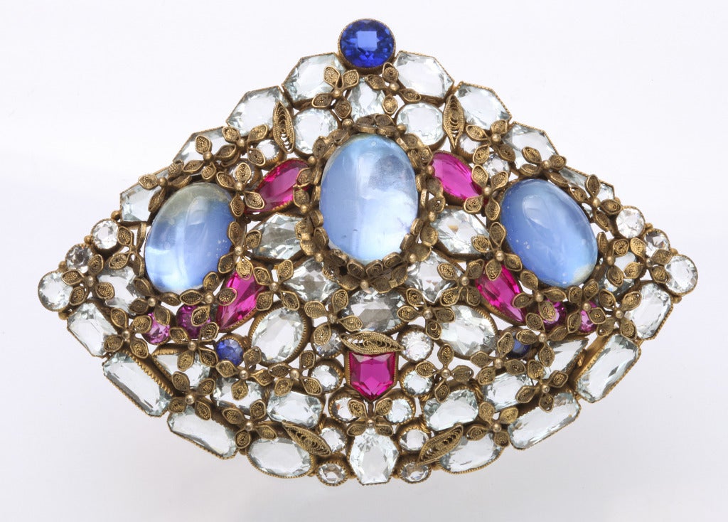 A spectacular gilt metal brooch set with faux rubies, aqua marines and moonstones, finished with a wire filigree floral pattern overall. Unsigned, but undoubtedly by Hobe. 2 1/2 inches x 3 1/2 inches.
From the Hollywood estate of a 50 year