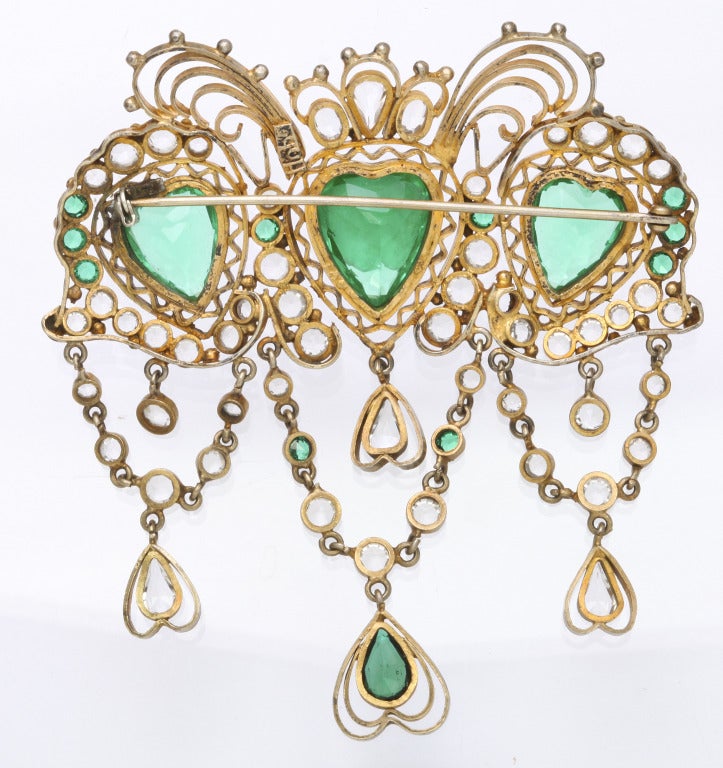Impressive 1930s Hobe brooch, of gilt filigree metal set with three large green heart shaped crystal jewels and multiple clear and green jewel accents. Marked Hobe on back. 3 1/4 in. x 3 3/4 in.