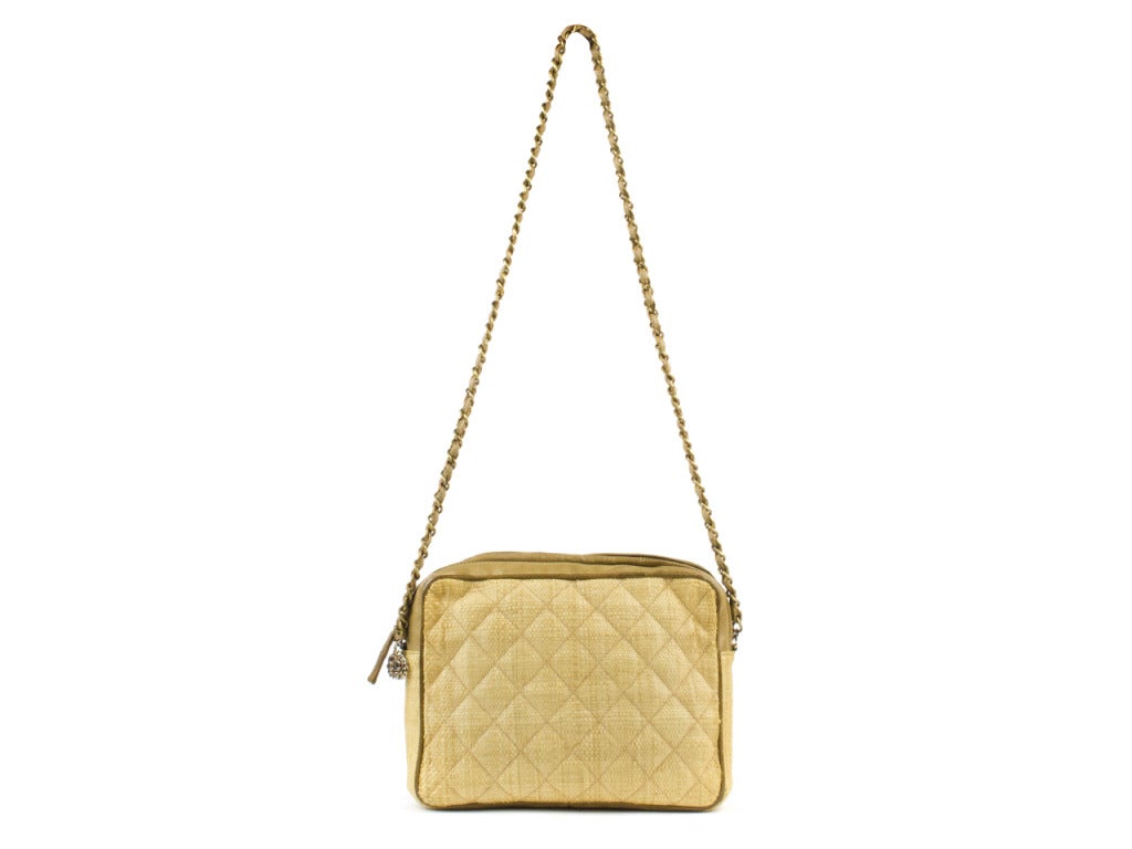 Give yourself a little vacation with this Chanel canvas bag. It has a beige wicker exterior with brown leather chain strap, and a unique braided pendant.