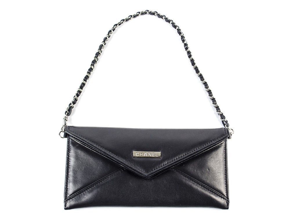 Perfect for a night out on the town! CHANEL Black Lambskin Leather 'Mademoiselle' Postcard Pochette features an envelope style with concealed magnetic snap closure, black leather with black leather lining, leather laced silvertone chain with one