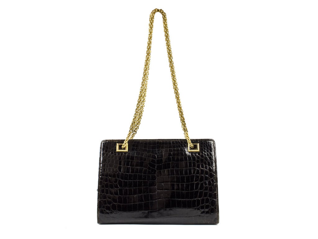 This bag will be sure to be a classic addition to any fashionistas collection! Gucci stands the test of time in this stunning black crocodile shoulder bag adorned with a double chain goldtone strap. The bag opens up to three separate compartments