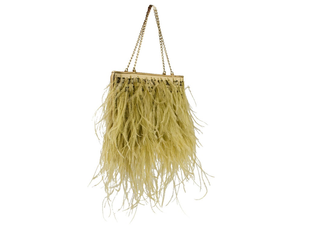 Turn heads with this gorgeous CHANEL beige satin frame with beige ostrich feathers throughout, matte gold-tone hardware, interlocking CC's beaded throughout, chain handles, gold metallic leather trim and magnetic closure.