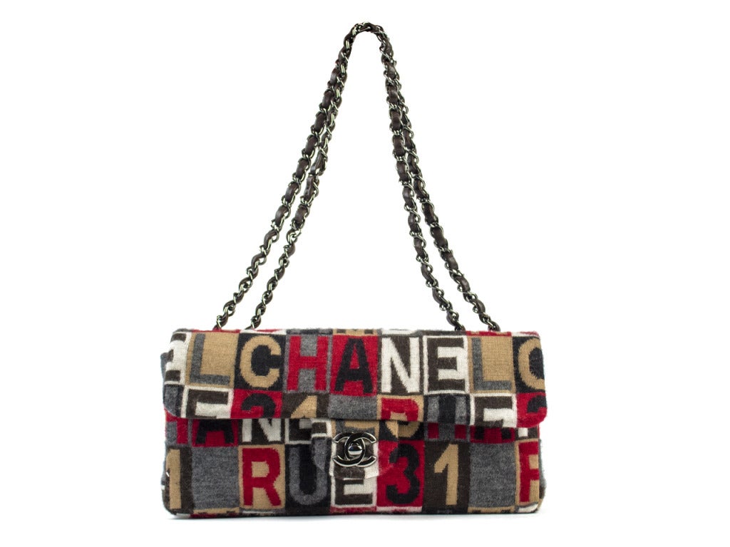 Dare to be different with this Chanel Rue 31 flap bag! Its fun lettering design, the variety of color and materials make it one to be noticed. It is made of cotton, while the chain link leather strap compliments it. H 5