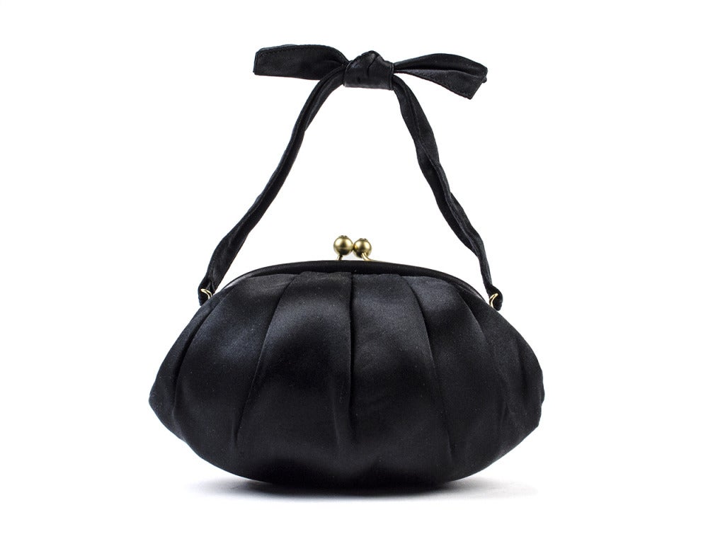 Complete your special occasion with the Chanel black satin clutch. The seashell-shaped evening bag features impeccable pleated black satin, a dainty bow-tied strap and gold clasp with interlocking CC details. An elegant and versatile clutch that