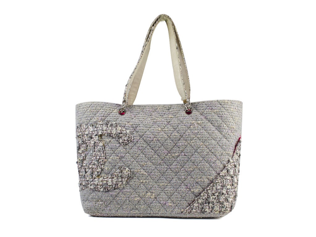 Carry everything you need for your day's many outfit changes in tweed glamour with the perfect hints of pink! The Chanel Cambon quilted tweed tote easily stores shoes, clothes and makeup in roomy and romantic style. Gray, lilac and beige tweed bag