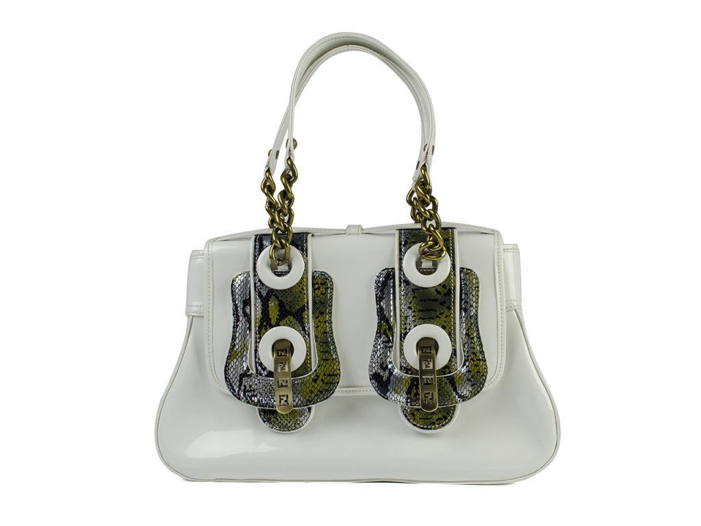 A multi-textured masterpiece! White patent leather flap bag in retro-inspired bell shape with two large silver and green snakeskin buckle details at front. Dark gold hardware pieces featuring Fendi FF logo cutouts pull through buckles to hold bag