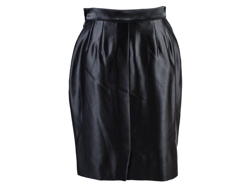 This black pleated skirt in iridescent satin-like polyester by Yves Saint Laurent shines with the savviness so befitting of you. Side zipper and single black button tuck you into this sophisticated piece of professional wear.

Measurements: Waist