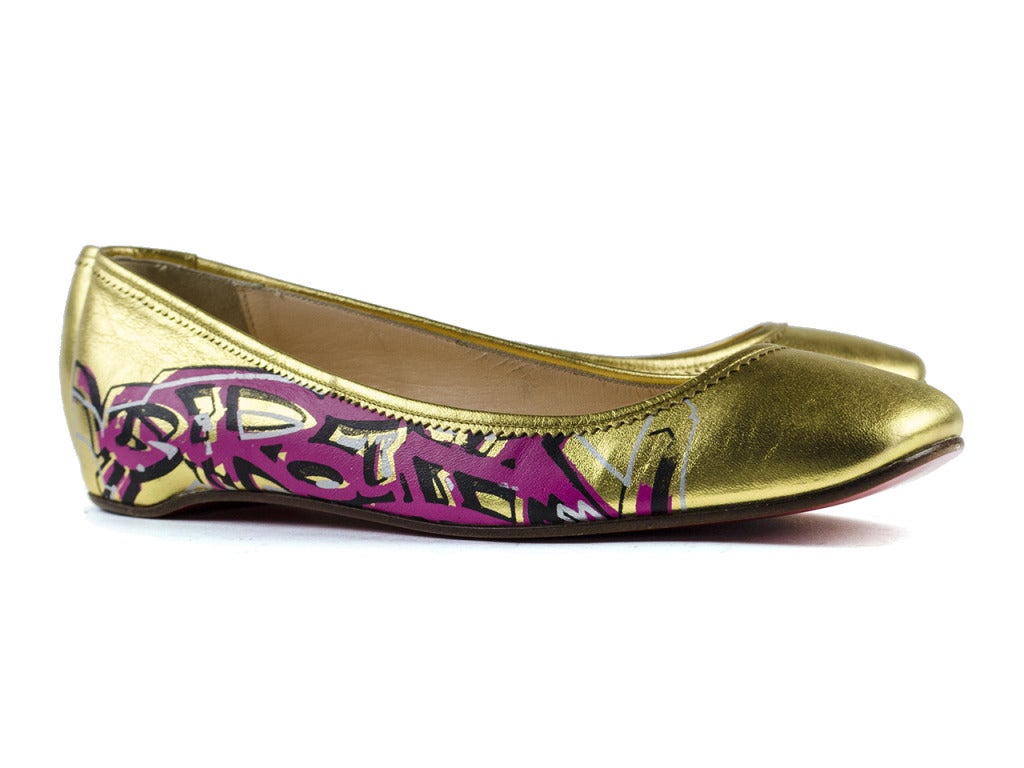 Make a statement in these Christian Louboutin 'Ballerina Graffiti' flats are done in a glistening gold with pink, silver and black graffiti details at side, round toe. Size 40.5.