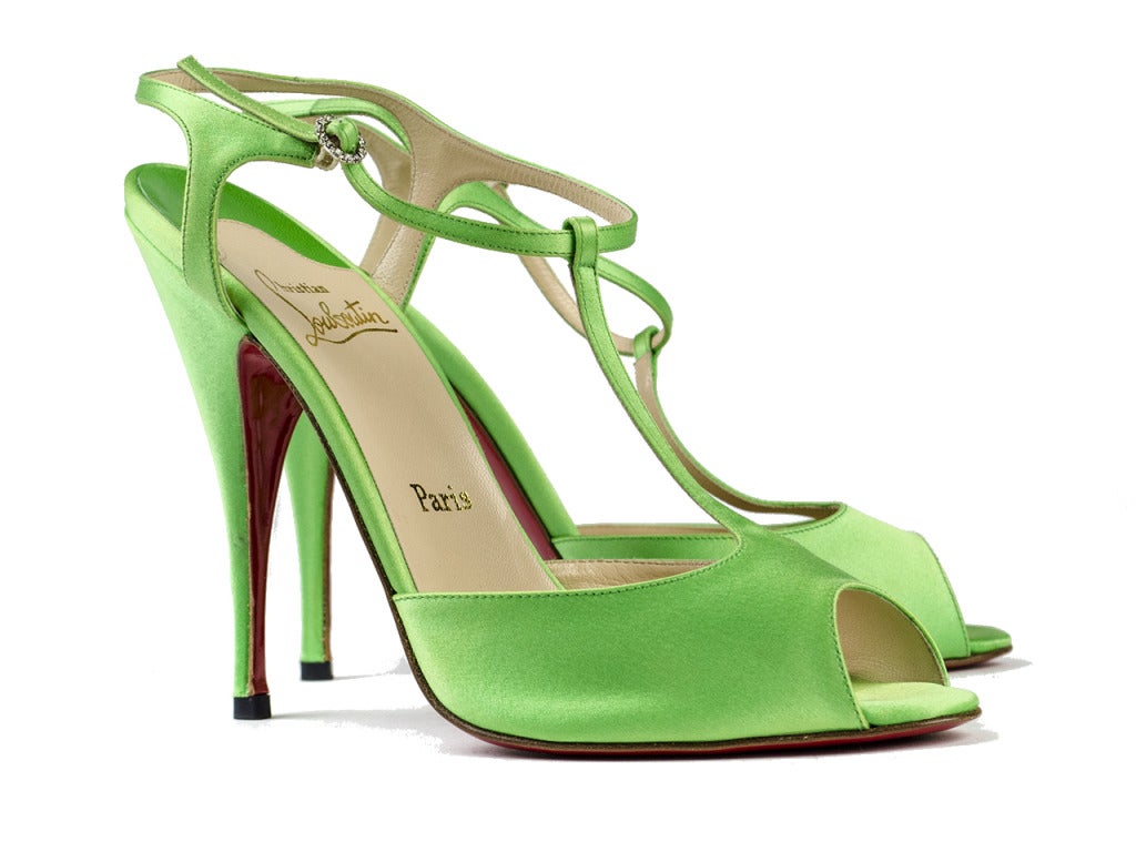 Step out in style in these perfect spring shoes! Christian Louboutin bright green t-strap sandals are perfectly paired with a spring dress! These shoes feature green satin throughout, t-strap style, rhinestone buckle at ankle. Heel measures