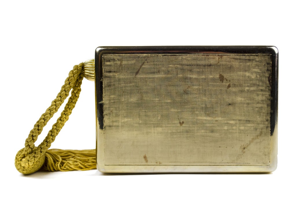 This Judith Leiber vintage wristlet clutch is absolutely timeless! It is box shaped with gold metal metal hardware and opens up like a jewelry box. The opening of the clutch has an elegant design outlined in Swarovski crystals. Has a rope tassel
