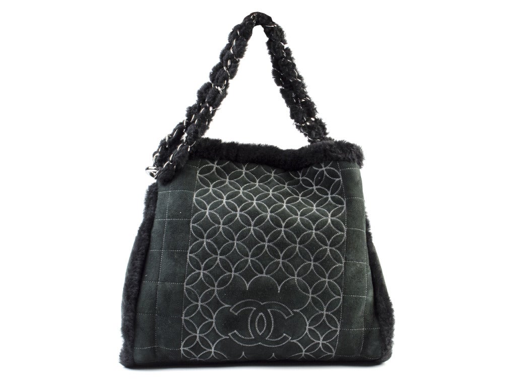For a warm and wintery look is this sheepskin and suede Chanel tote. It is a black handbag that has a unique stitched design with CC logo, furry lining, and a silver accent chain strap. Also includes a mini change purse inside. 
Dimensions: 12