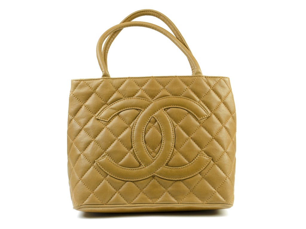 This Chanel handbag is made of smooth Caviar leather and quilted to perfection. With its tan coloring, jumbo CC logo, and quality size, it is the best bag to acquire for any occasion. Has outside pocket slip and two inside pockets; one with a