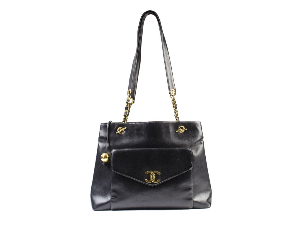 This Chanel tote bag has soft lambskin leather exterior with gold accents. Has three separate compartments, one of which is enclosed with a zipper that presents a gold quilted ball medallion. Also has an outside pocket with flap that has a CC logo
