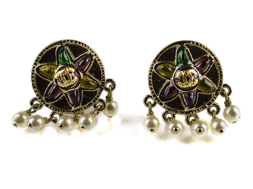 Tons of fun details in a bite-sized pair of earrings! The Chanel 07P tribal pearl drop earrings grace the ears with dime-sized light gold medallions encrusted with six-petal yellow, purple and green flowers with interlocking CC symbols at center.