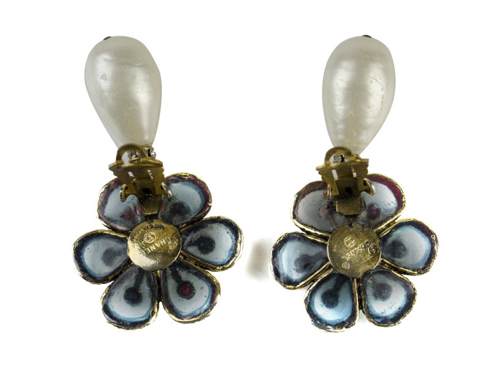 Your Sunday best will look even better with the vintage Chanel floral pearl drop earrings added to them. Tear drop pearls dangle from a flower clip-on earring with light blue poured glass petals and rhinestone details.

Measurements: 2.5