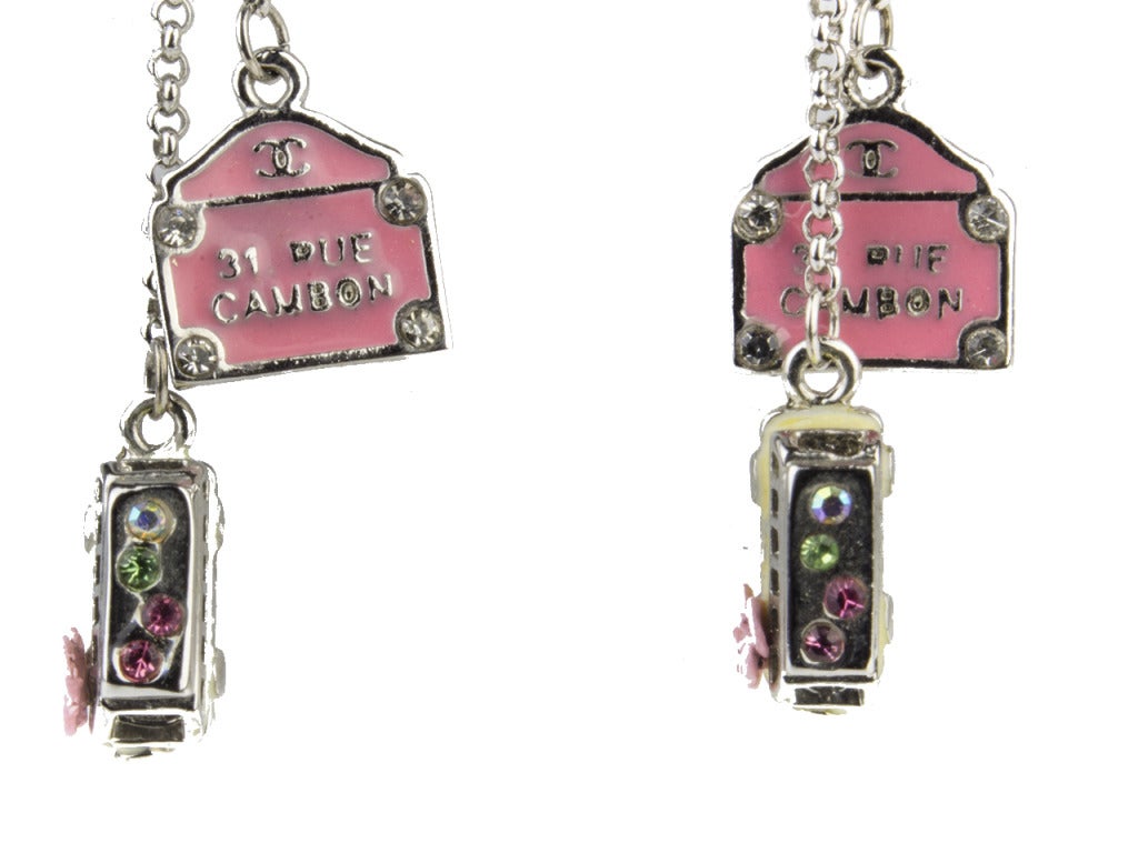 Jet set through Europe in luxurious style with the vintage Chanel 2210 dangle earrings serving as inspiration. Rhinestone- and flower-adorned silver bus charms and pink luggage tags with interlocking CC symbols and 31 RUE CAMBON displayed in