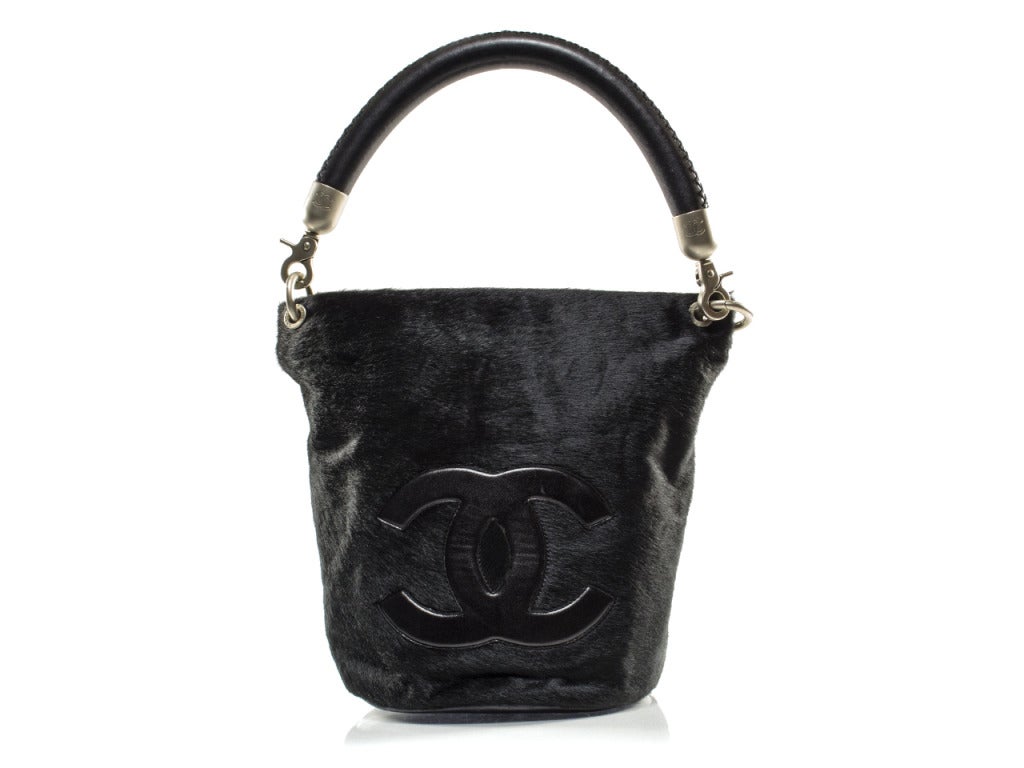 Pull on your fur-lined peacoat and throw your winter essentials into the Chanel fur bucket bag tote and you've got a cozy chic look all the chilly months through. This unique tote features black fur outer body with large black leather interlocking