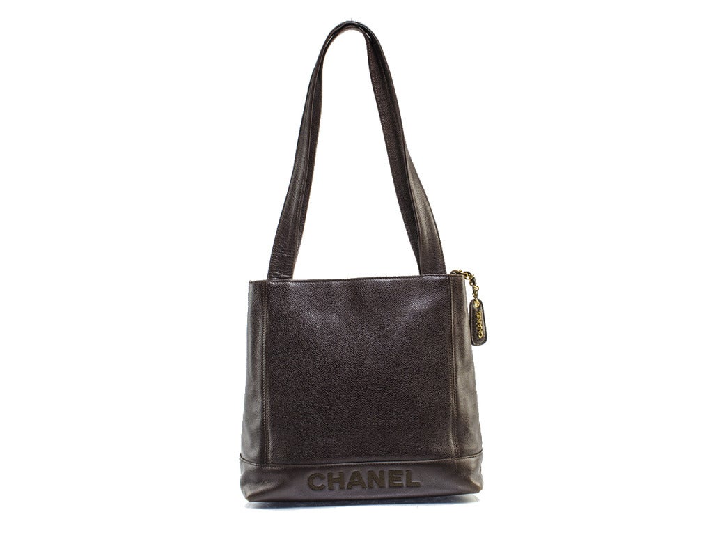 Chocolate brown riding boots and flats have met their match in the Chanel vintage distressed tote. This casual shoulder bag features pebbled leather with CHANEL embroidered in signature typeface at front and back and plenty of utility throughout.