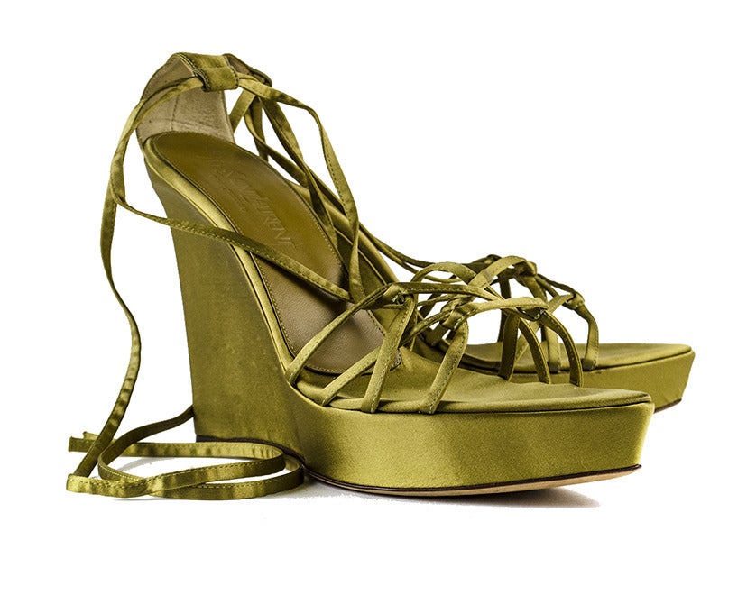 Tie up these golden Yves Saint Laurent satin wedges and get ready to show off your legs at a classy cocktail party or evening on the town. Thin straps are delicately intertwined at the vamp, criss-cross at the middle of the foot and tie up the calf