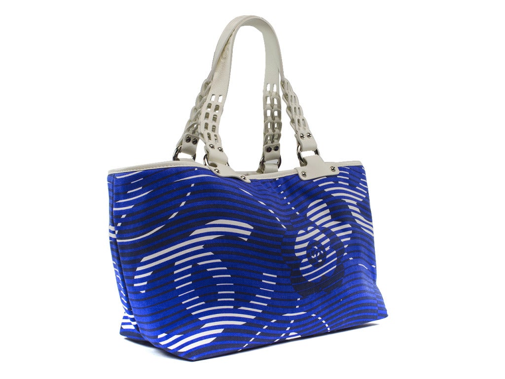 Step into summer in this fun Chanel tote in monochromatic blue hues! This tote features a subtle Chanel 'CC' print throughout the exterior with pebbled leather white handles also with 'CHANEL' written across. Interior features one zip pocket and one