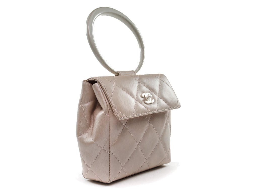 Extremely rare! Chanel pearlized pink tote is perfect for an evening out or with a chic summer dress! This gorgeous bag features quintessential diamond pattern throughout, flap detail, pearlized white round handle, white Chanel 'CC' button clasp.