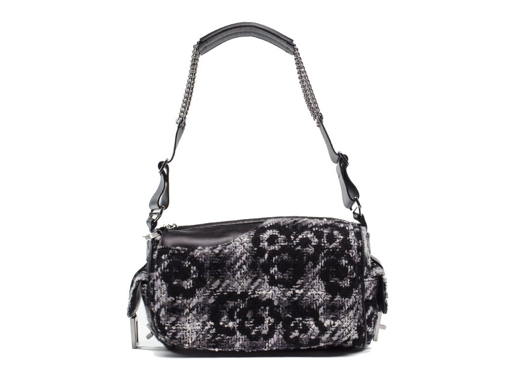 A twist on the traditional flap! This Chanel tweed boucle bag is featured in a barrel style with one front flap, two side pockets with Chanel reissue style lock and one front pocket. Mixed leather chain silver chain handle. Zip top closure with