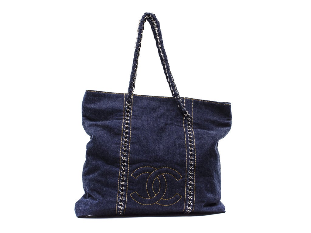 Perfect for summer! This Chanel denim tote will be your go to bag this summer! Pair it with shorts or a cute sundress and you're good to go! This tote is featured in dark denim with contrasting yellow stitching throughout, interlocking Chanel 'CC'