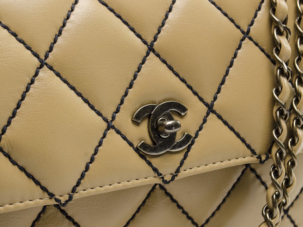 A unique flap that cannot be found anywhere else---this Chanel bag will be sure to delight! Featured in beige lambskin leather with contrasting black stitching, silver tone brushed hardware, double strap detailing and one back pouch pocket. Interior