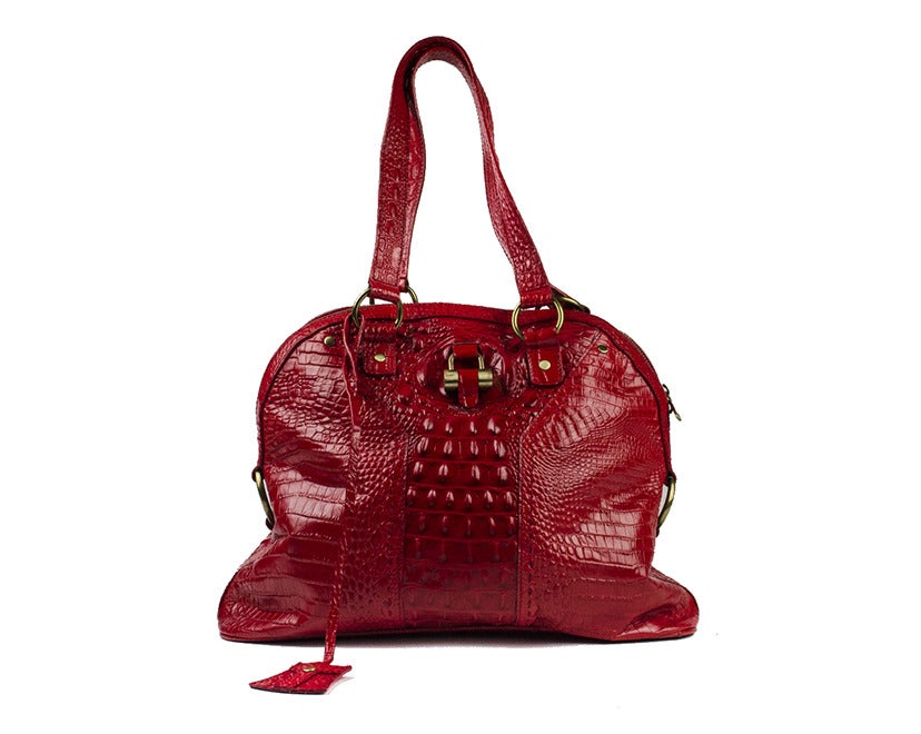 Add a pop of color and a pop of refinement to any outfit with the Yves Saint Laurent crocodile Muse bag. Fire engine red with gold accents, the bag is the perfect accessory, with timeless glamour in every curve. Interior features one zippered and