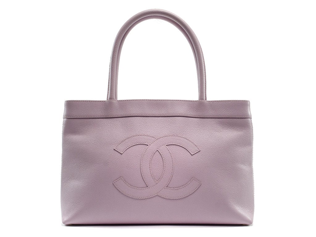 Complete the polished look of a fresh floral print cardigan and white slacks with the Chanel Timeless caviar tote. Pastel pink caviar leather enwraps a perfectly sized tote with large interlocking CC symbol embroidered at front and champagne