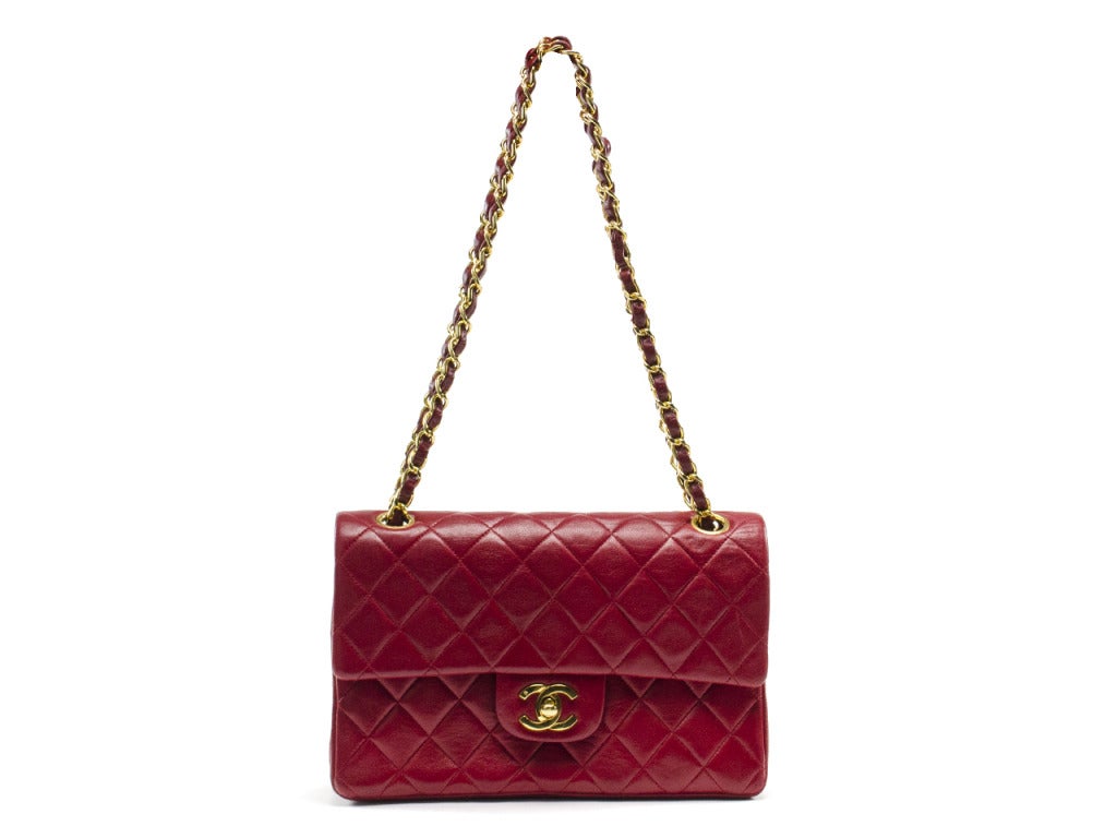 Every woman needs a signature red bag, and none rivals the classic Chanel flap. Quilted red leather shoulder bag features interior and exterior flap with iconic gold interlocking CC symbol charm at turnlock of exterior flap and matching symbol