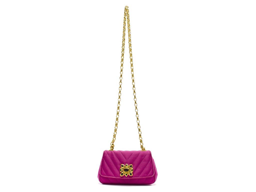 Dazzle up a little black dress with the vintage Chanel pink satin gripoix evening bag. Magenta satin flap bag is stitched with chevron pattern and adorned with a stunning yellow gold brooch with black, blue and green gripoix poured glass details.