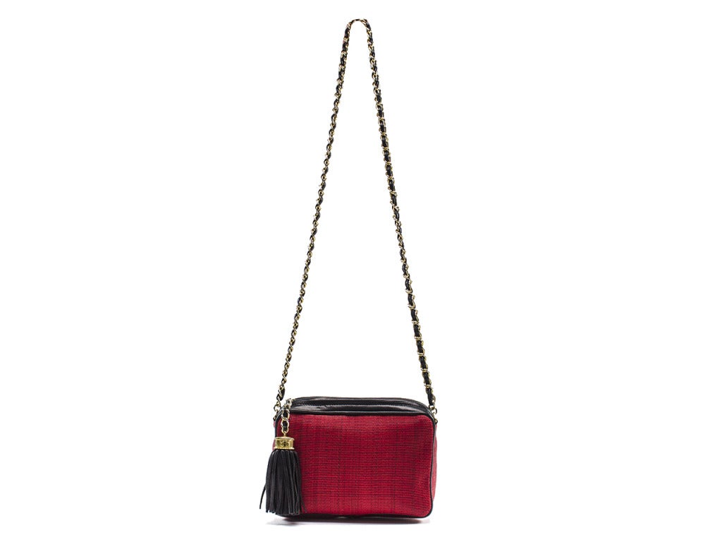 A picture-perfect camera bag sure to add quaint vintage character to your Chanel collection. This vintage Chanel camera bag features a spacious rectangle shape constructed out of red canvas and black leather, with black leather tassel zipper pull
