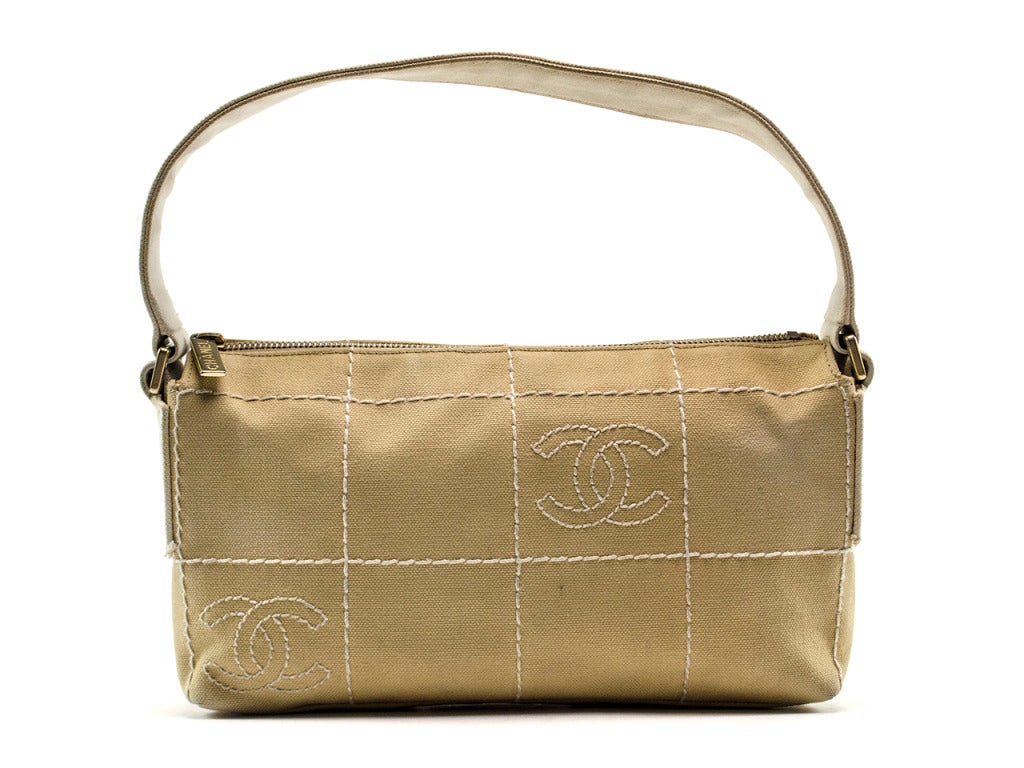 The perfect bag for a day at the shore! The Chanel canvas shoulder bag features beige canvas construction detailed with white-thread square quilt pattern and interlocking CCs embroidered inside two squares on front and back. Carry your beach