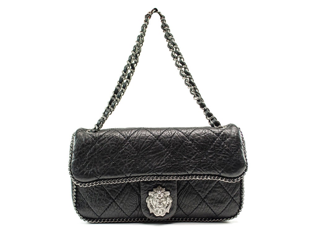 This limited edition Chanel flap is gothic glam in all the right places! The quilted black textured leather shoulder bag is lined with silver chain link detailing and crowned with the fierce face of a lion, it's mouth silenced with the power of the