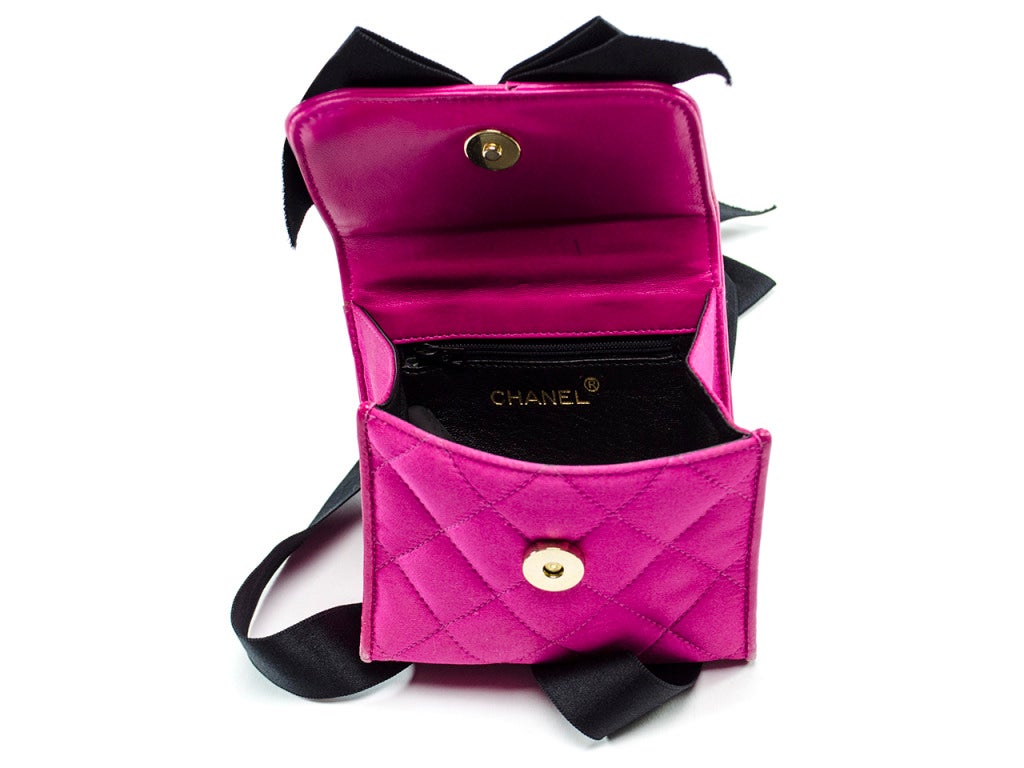Super hard to find! Chanel pink satin bag with a black bow is perfect for a night out on the town. Tuck the strap in and wear as a clutch or leave out and wear as a shoulder bag.Interior features one zipper pocket.

Dimensions: 5.25