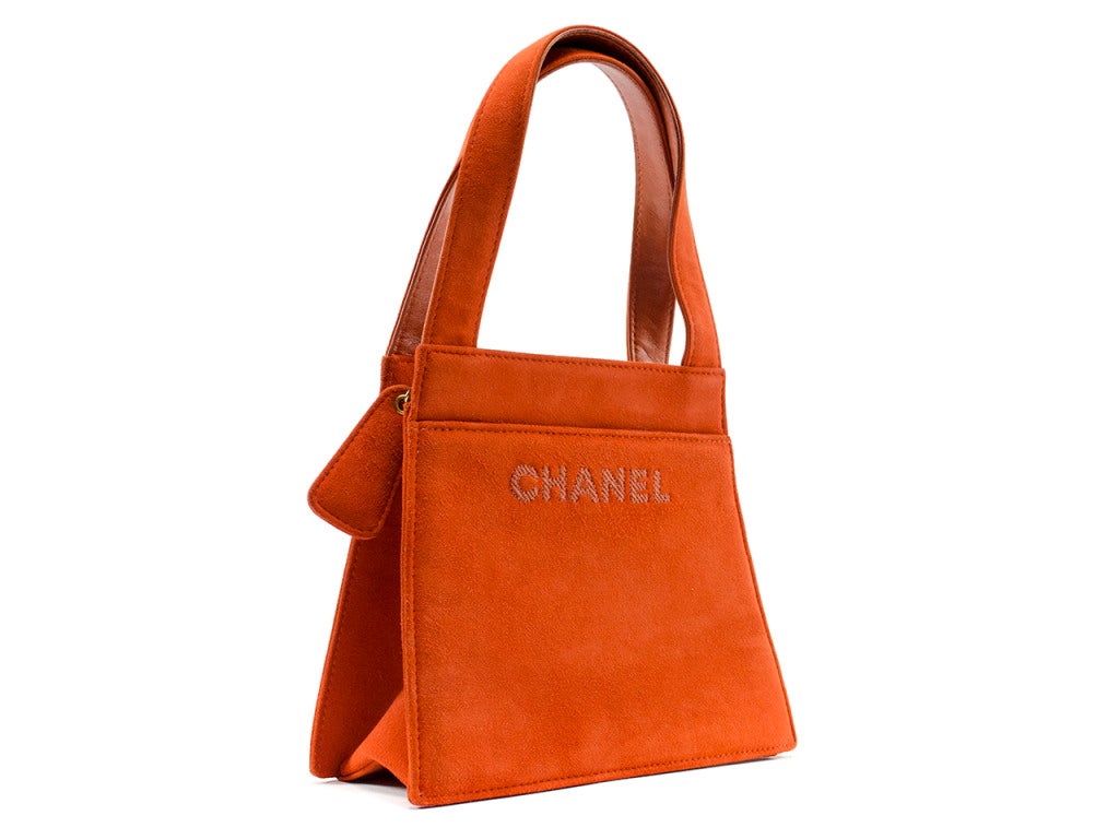 Perfect for toting around town, this Chanel bag features orange suede throughout with two exterior pockets, zip top closure. Interior features one pouch pocket.

Dimensions: 7.25