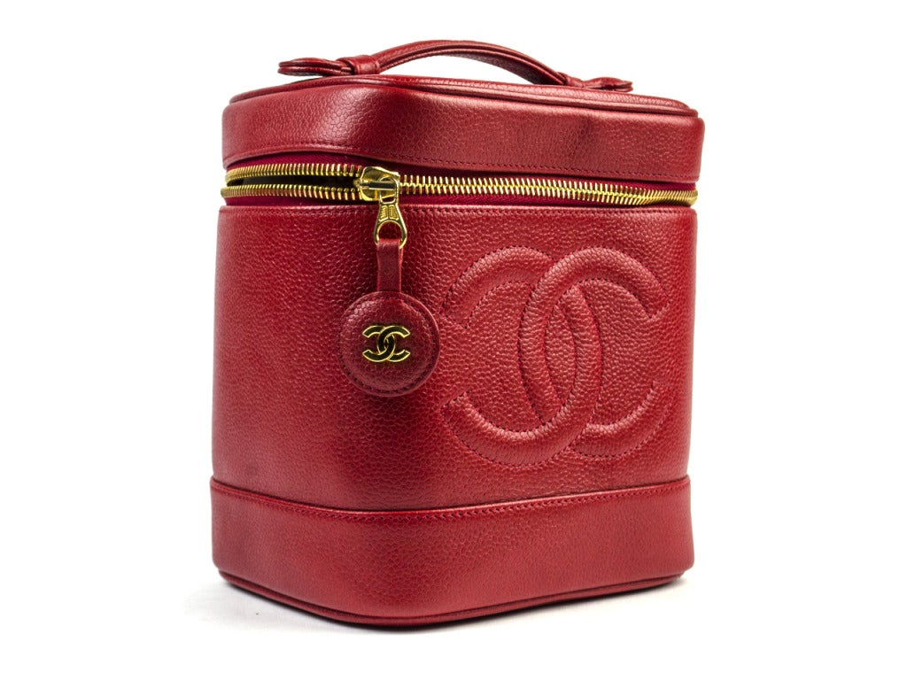 Stunning & flawless Chanel 90's tomato red caviar leather vanity features a short top handle, zip around top, iconic interlocking 'CC' detail at front and gorgeous 'CC' pull medallion zipper detailing.