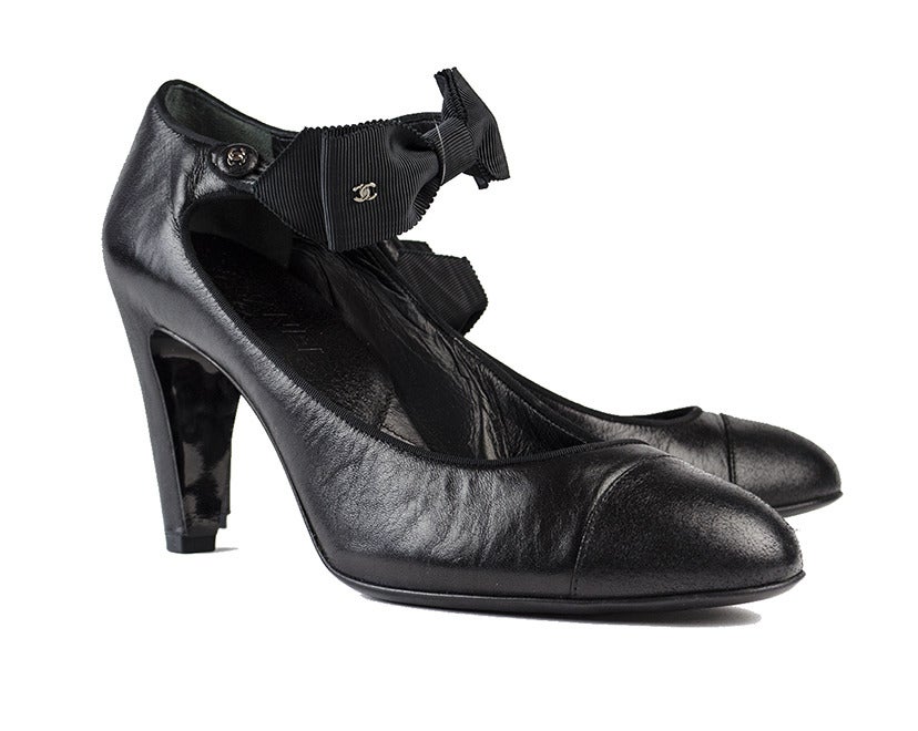 Pair the romantic Chanel black leather ankle bow heels with a cocktail dress and stylish winter coat for an elegant evening out to the theater with your beau. Silver interlocking CC symbols adorn the bow and the strap button and stitching at the