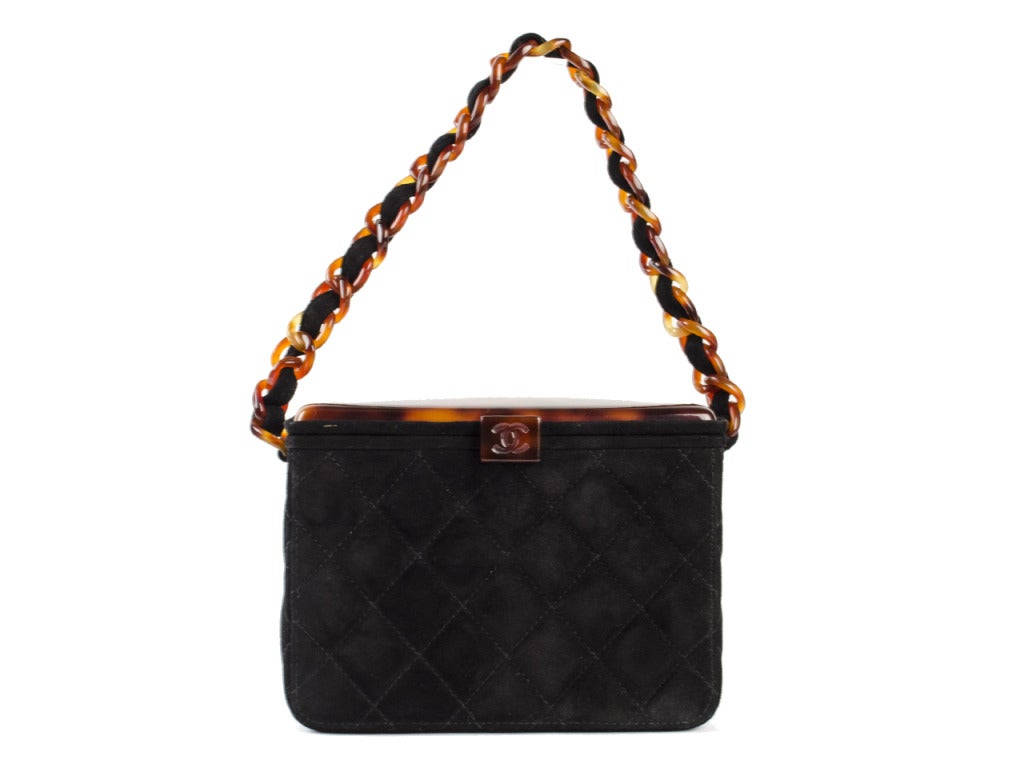 This Chanel Suede Box Bag is perfect for the vintage-loving fashionista! Perfect for a night out, it features black quilted suede with a unique tortoise shell resin top and a boxy design. The clasp is engraved with the CC logo and this bag is