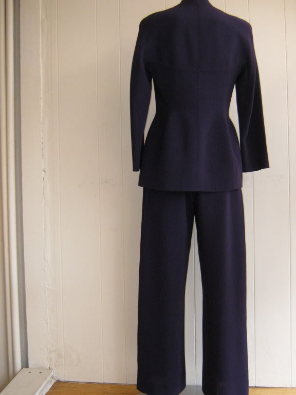 Modernist deep purple pant suit with four raised brushed silver snap buttons on the front. The suit has a scoop neckline which can be worn on its own and a jacket accented with twin flaps on the bottom. 

The pants have slant pockets on each side
