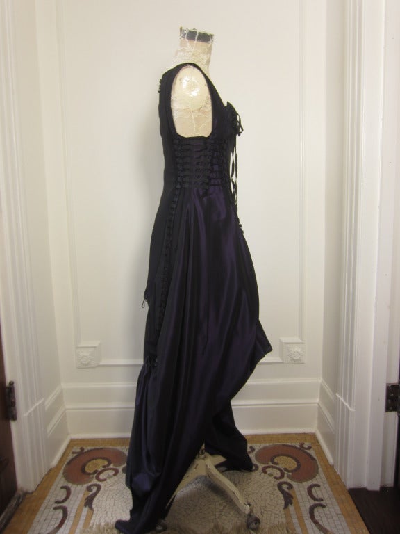 This stunning evening dress will bring the room to a halt. The dramatic bustle effect in the back with the shortened hemline in the front adds dimension to this otherwise purple black dress. It is simple to fit as it can be tightened in the corset