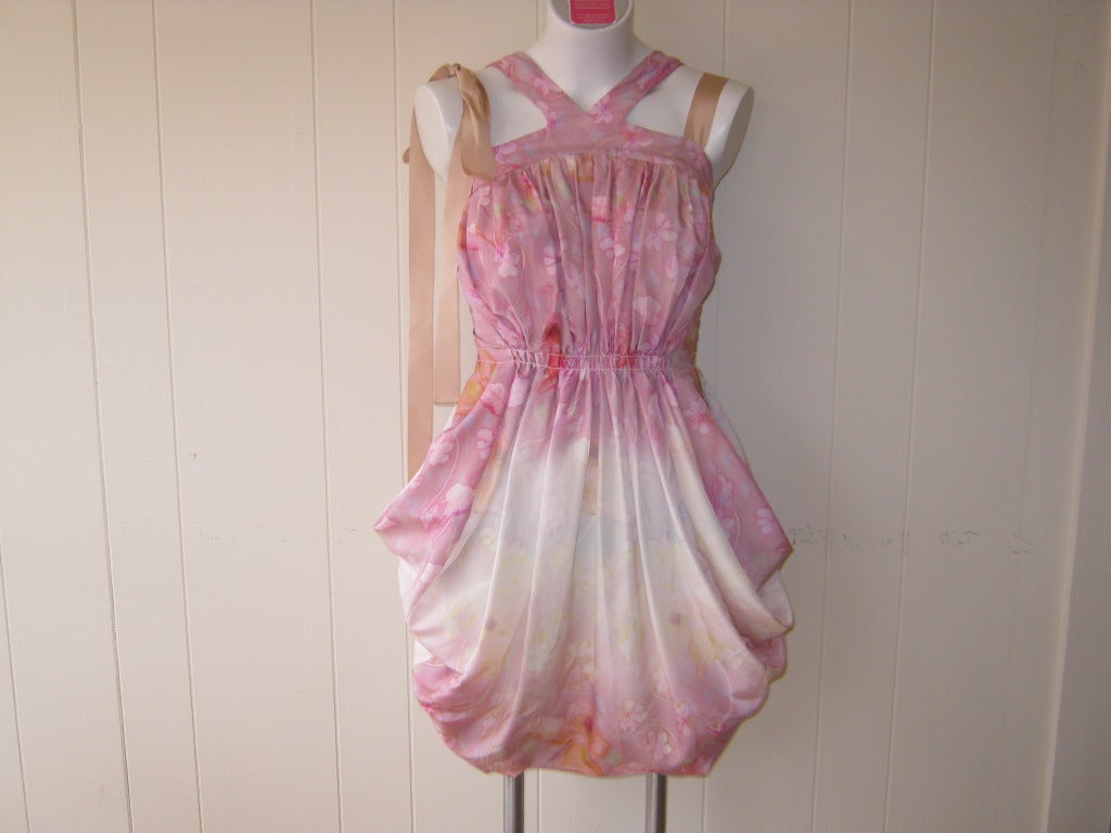This dress is like a water colour with its pale pink floral design, and is signed throughout with the Nina Ricci signature.

The dress has four wide shoulder straps, loosely pleated bodice and whimsical blouson skirt.

There is no size marked