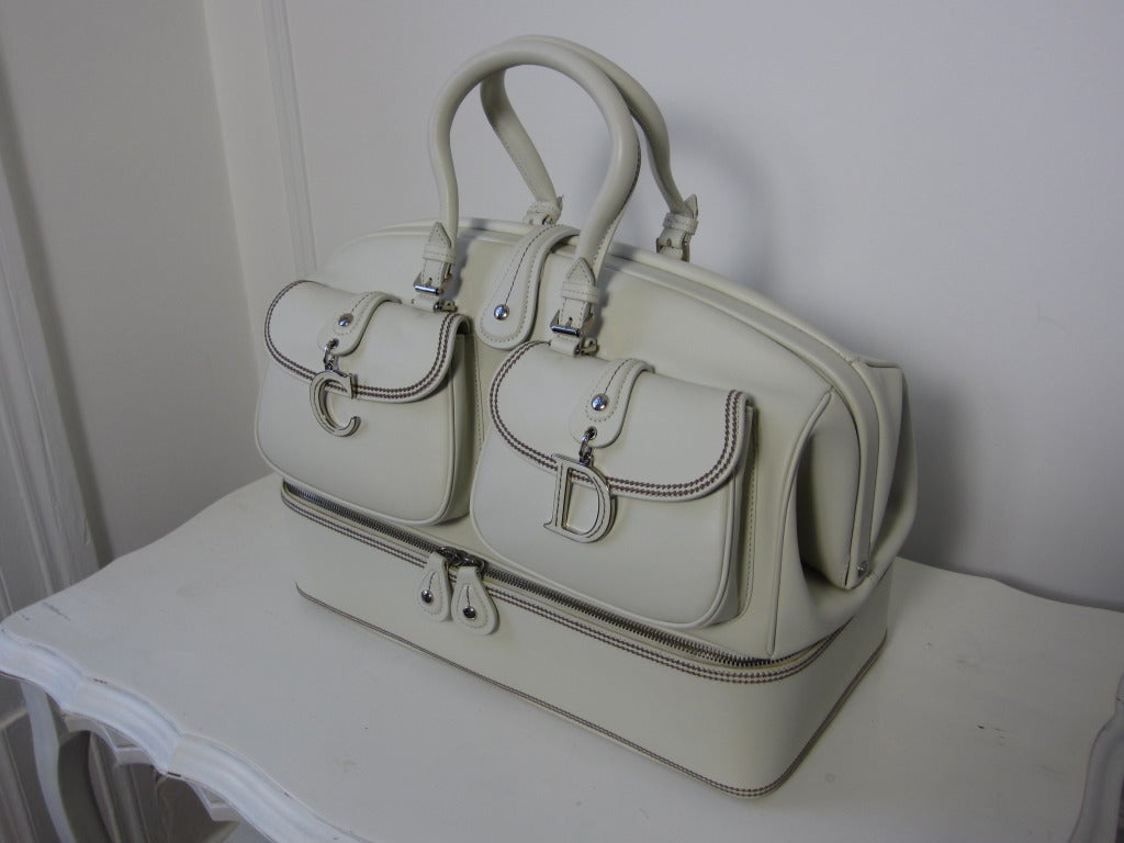 One of a kind different and  eye catching this bag features the finest calfskin leather with decorative stitching.
The focus on  this iconic doctor's bag shape are the two snapped front pockets with dangling silver and cream 