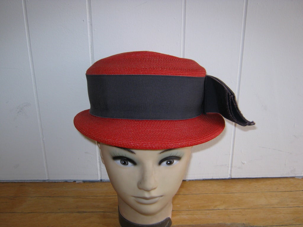 From the makers of the famous cowboy hats, this is a delightful red tightly woven straw boater, with a black gros grain ribbon above a slightly rounded brim and a gros grain band on the inside which has the Stetson logo and indicates a 22