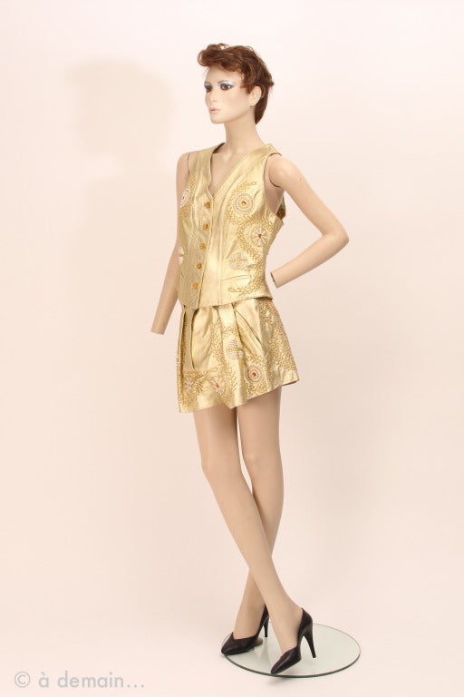 Jean-Claude Jitrois Paris, made in France gold leather set of a  sleeveless jacket and a short with belt, decorated with flower made by white and gold pearls and orange cabochons. 

A special set from the 1980s, disco time with a very trendy gold